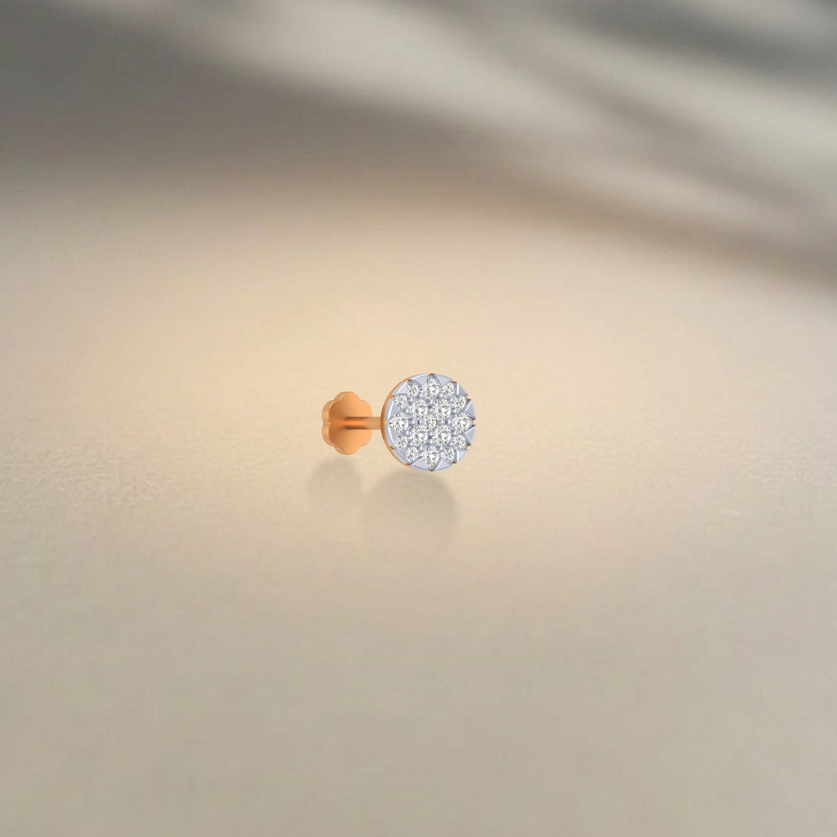 A single round nose stud with a pavé-set clear stone, shown on a soft beige background with a soft shadow.