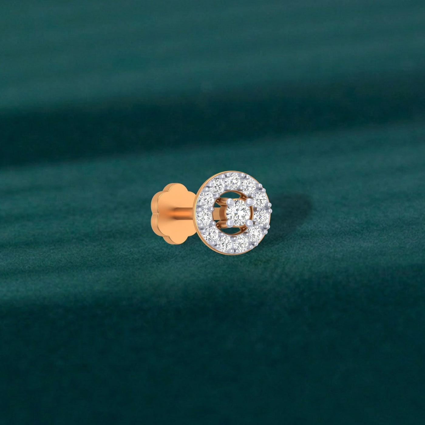 Yellow gold and diamond stud nosepin with a circular design on a teal fabric background