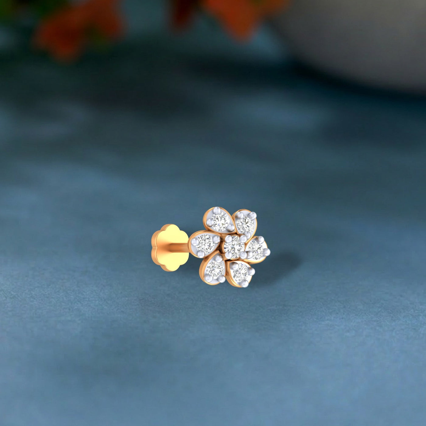Gold and diamond stud nose pin on a blue background
