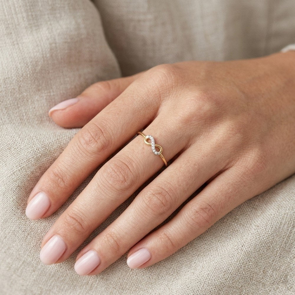 Hand wearing a gold and diamond infinity ring.