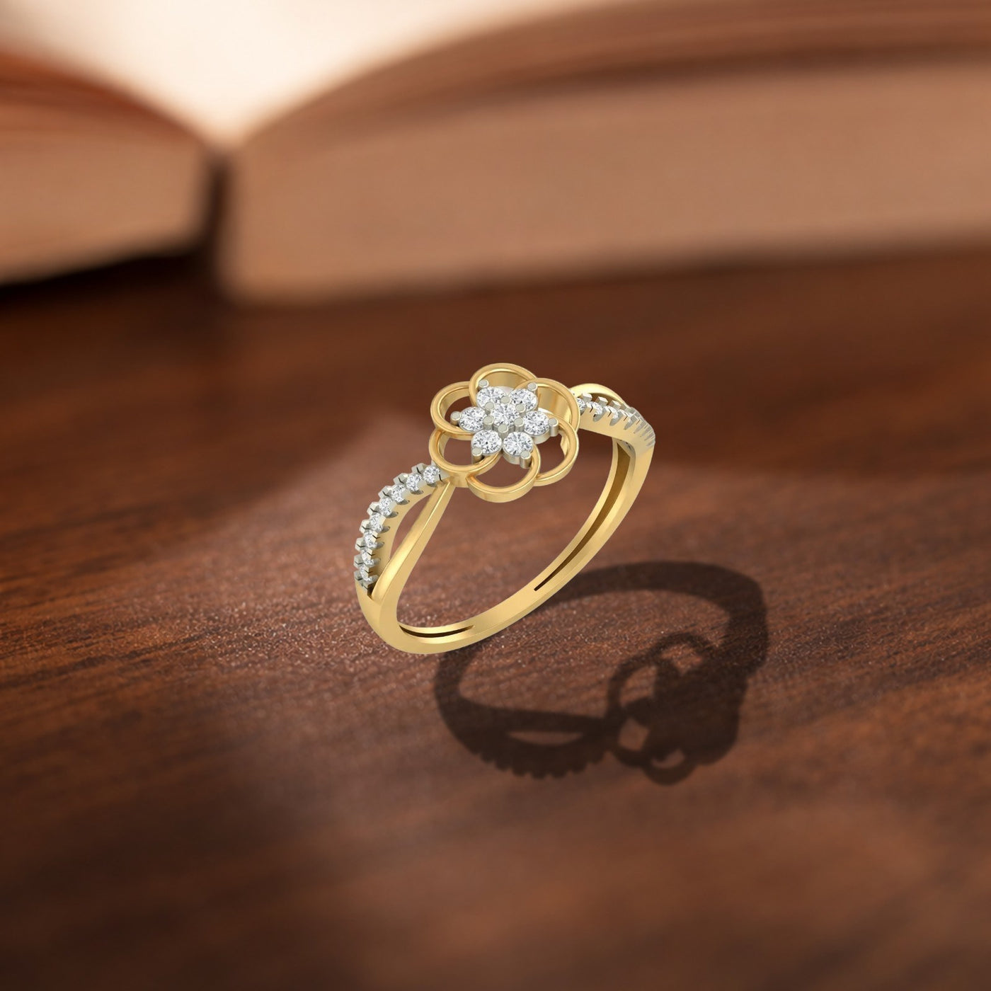 A gold ring with a center floral design, displayed on a wooden surface.
