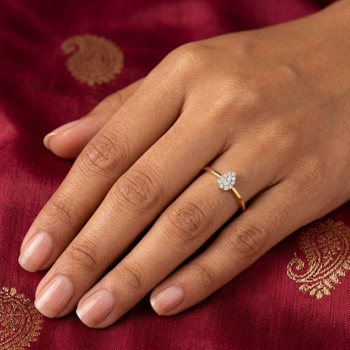 Gold and diamond with teardrop shaped cluster setting on person finger.
