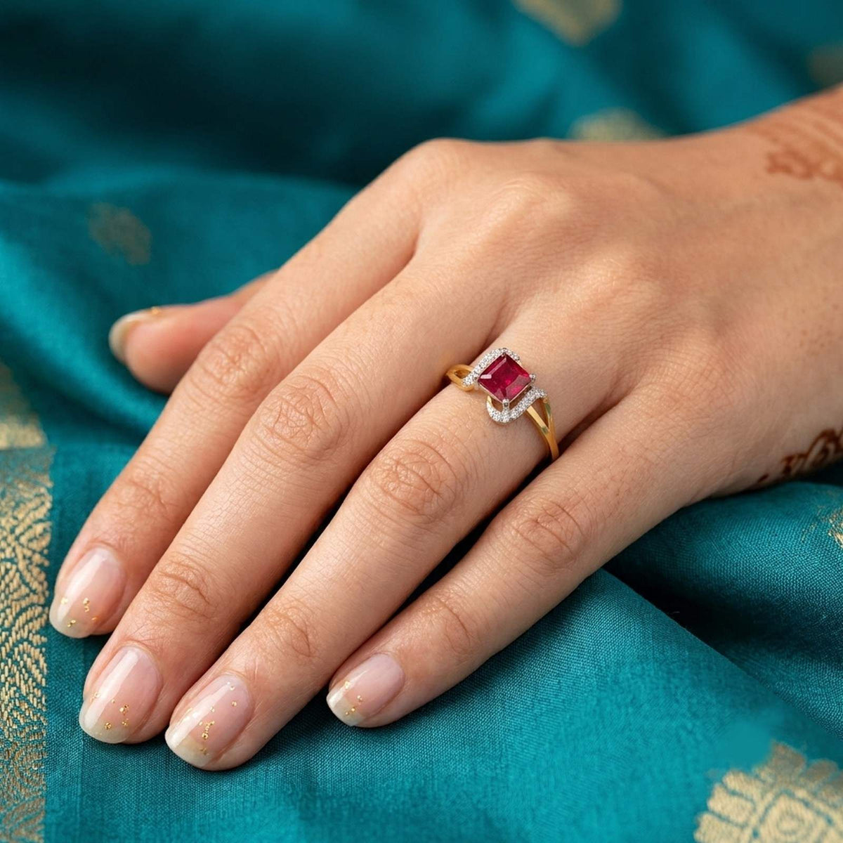 Gold ring featuring a square-cut ruby gemstone, shown on a blue saree.