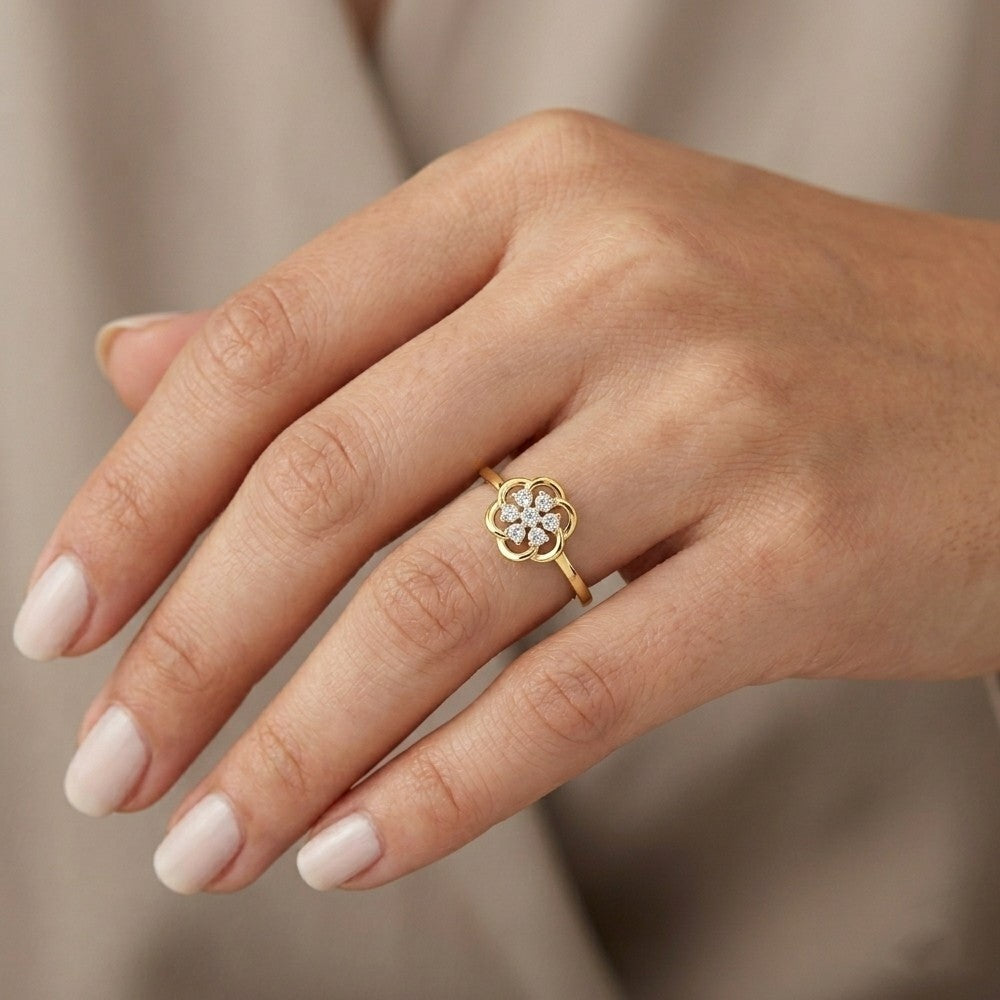Gold ring with a diamond on a person's finger against a neutral background