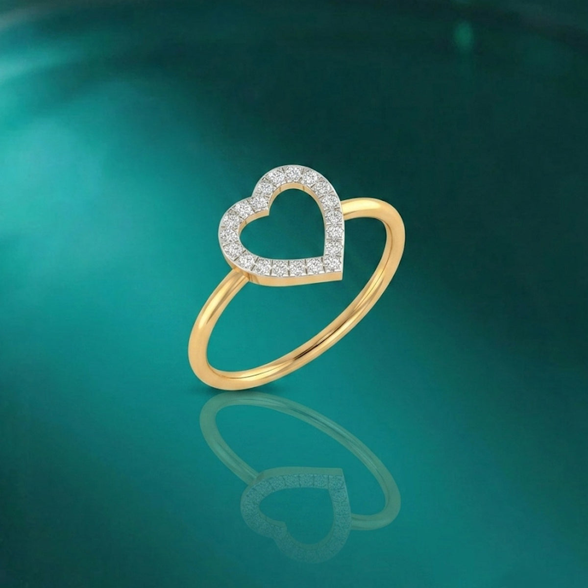 Gold ring with a heart design on a person's finger against a reflective surface