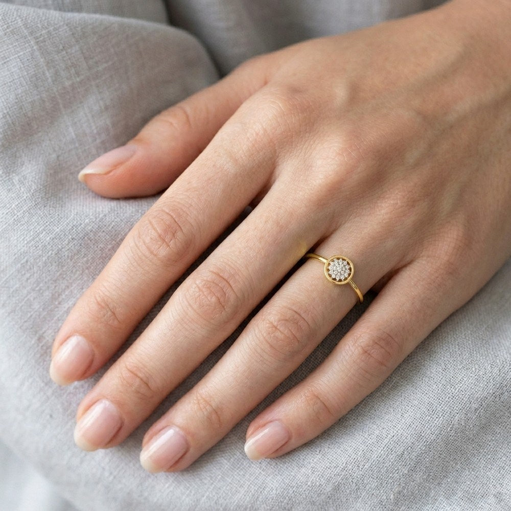 Gold and diamond with round-shaped and center floral cluster setting on a person's finger.