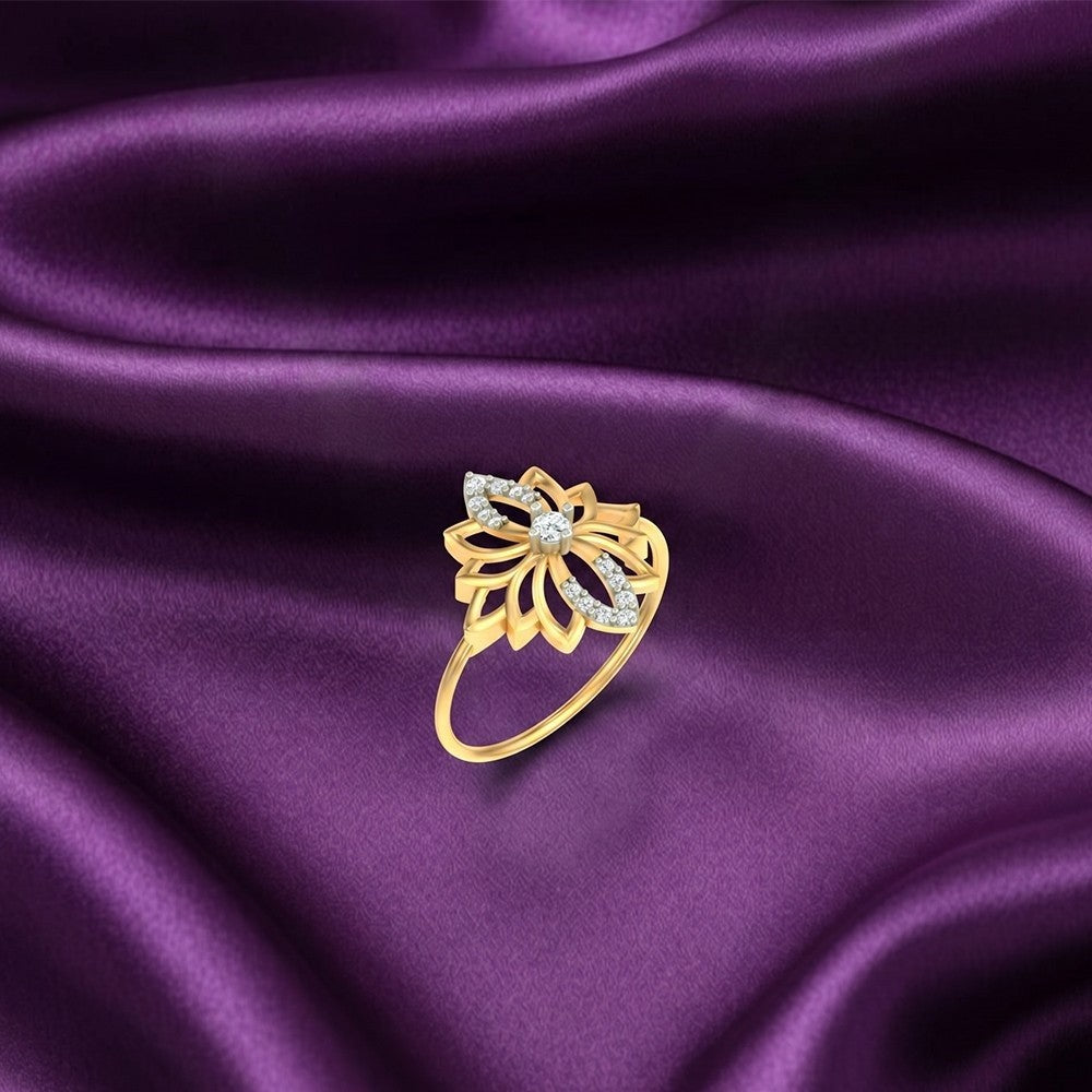 A gold ring featuring a stylized lotus flower design, shown on a purple satin surface.