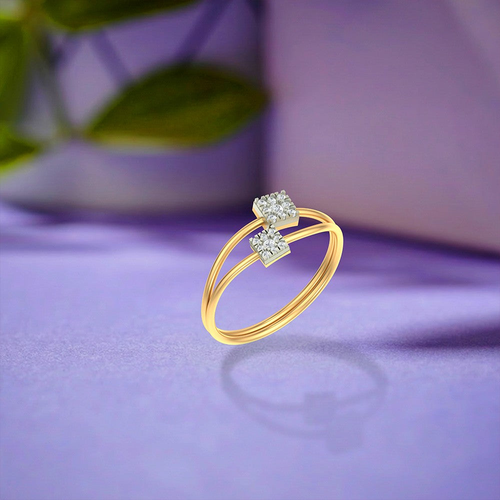 Gold and diamond ring with two square cluster on a purple surface.