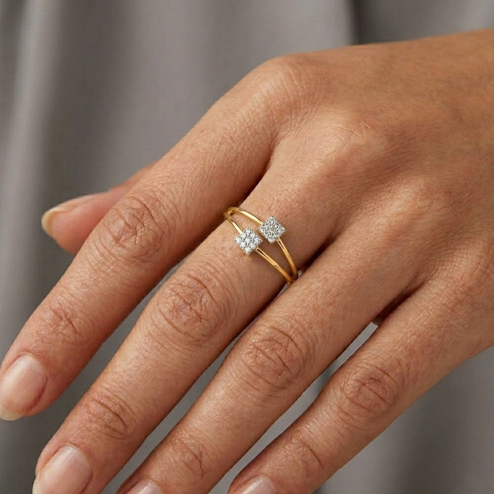 Hand wearing a gold ring with two diamonds on a neutral background