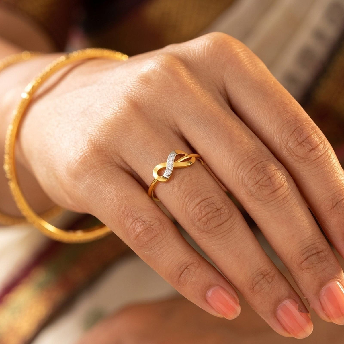 Gold and diamond with infinity design on a person's finger.