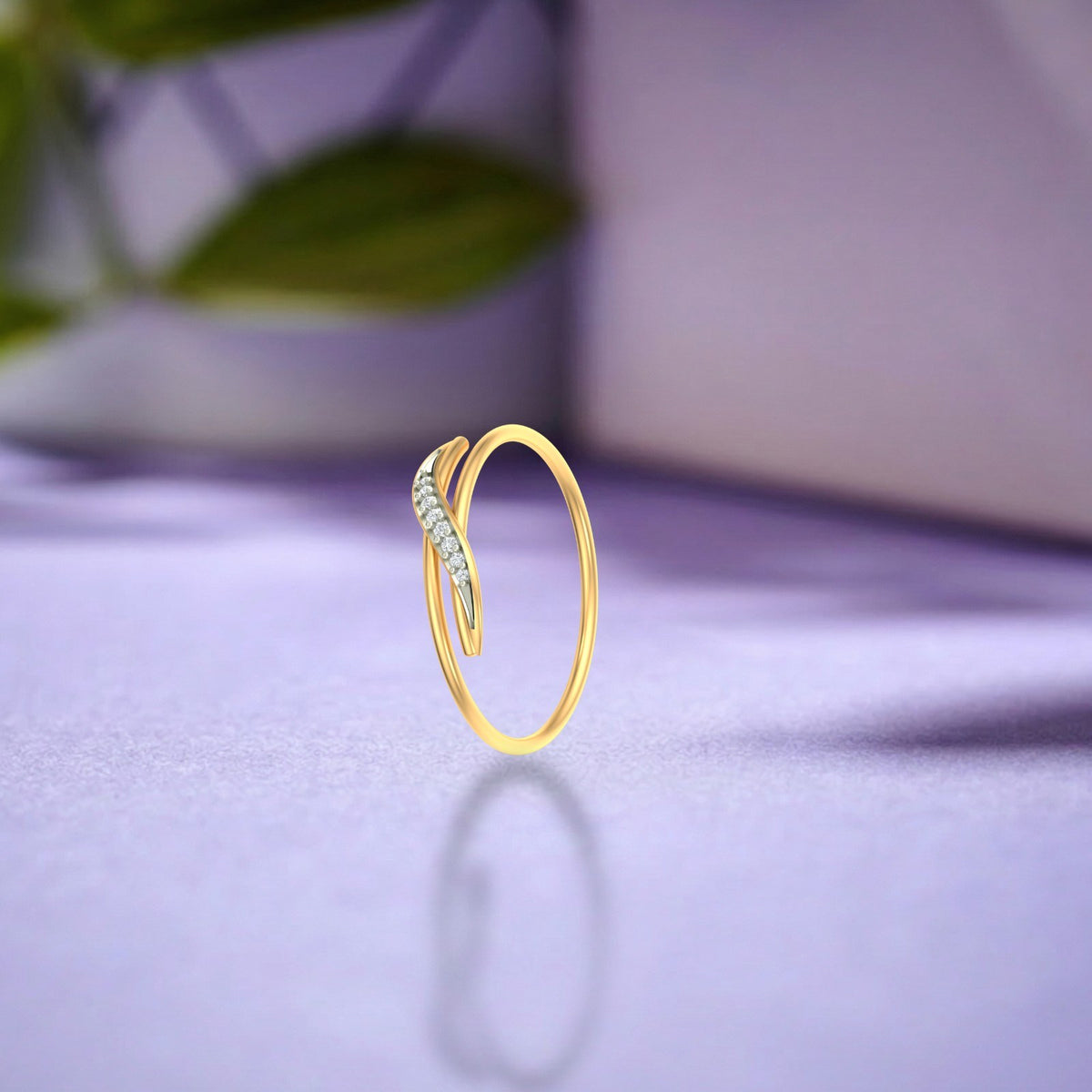 Gold and diamond women's ring on a purple surface.