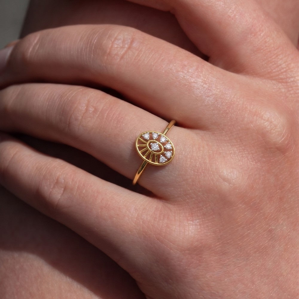 A close-up of a hand wearing a delicate yellow gold ring on the ring finger
