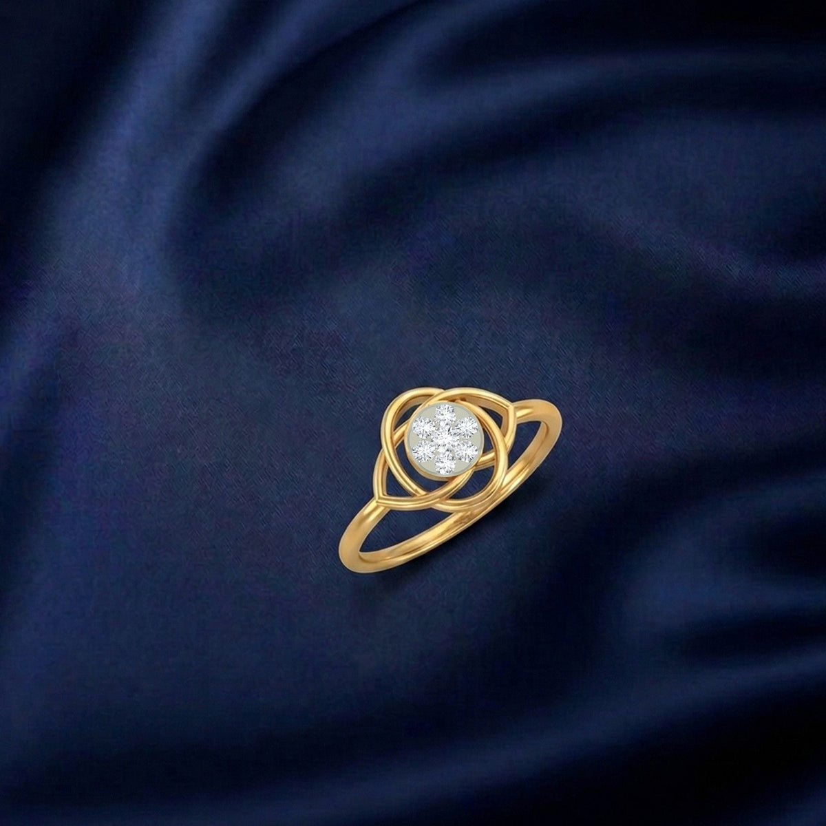 A gold ring with a central round cluster, displayed on a dark navy blue satin fabric background.