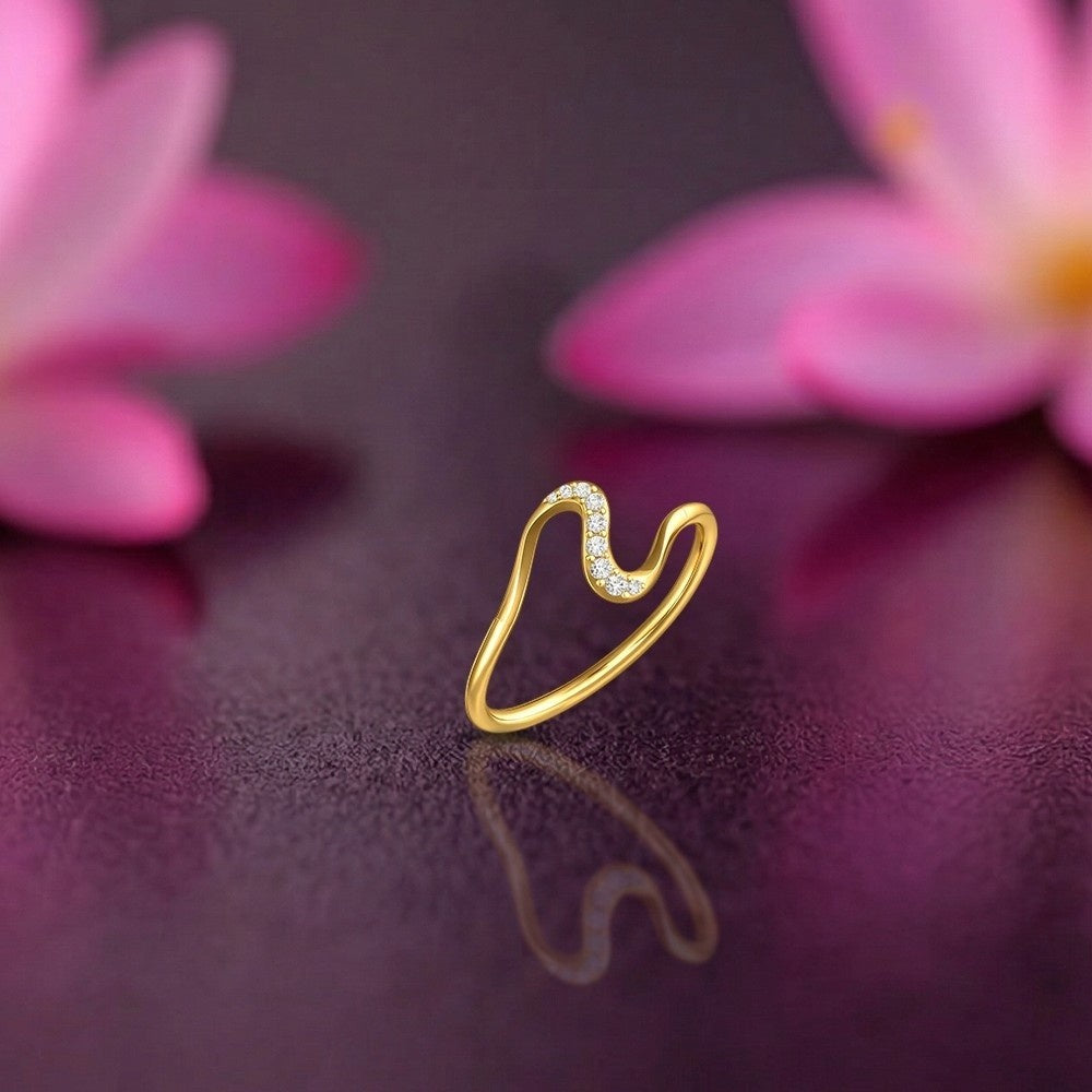 Gold ring with small diamonds on a dark surface with pink flowers in the background