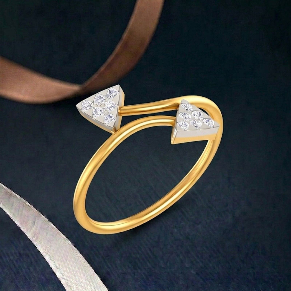 Gold ring with two triangular cluster settings on a teal surface.