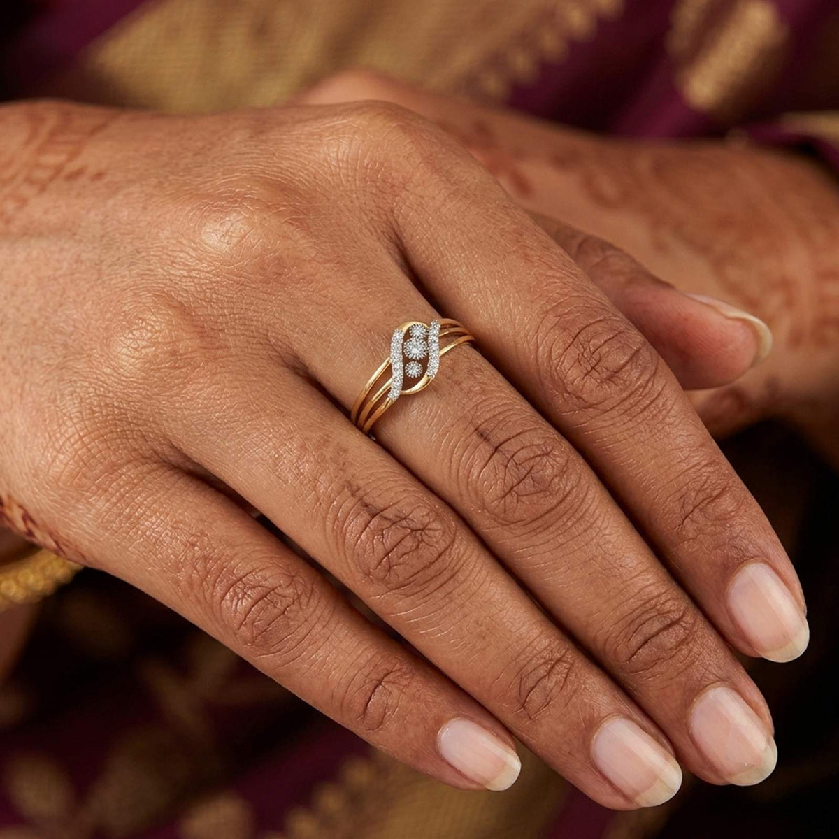 Gold ring with floral design on a person's finger
