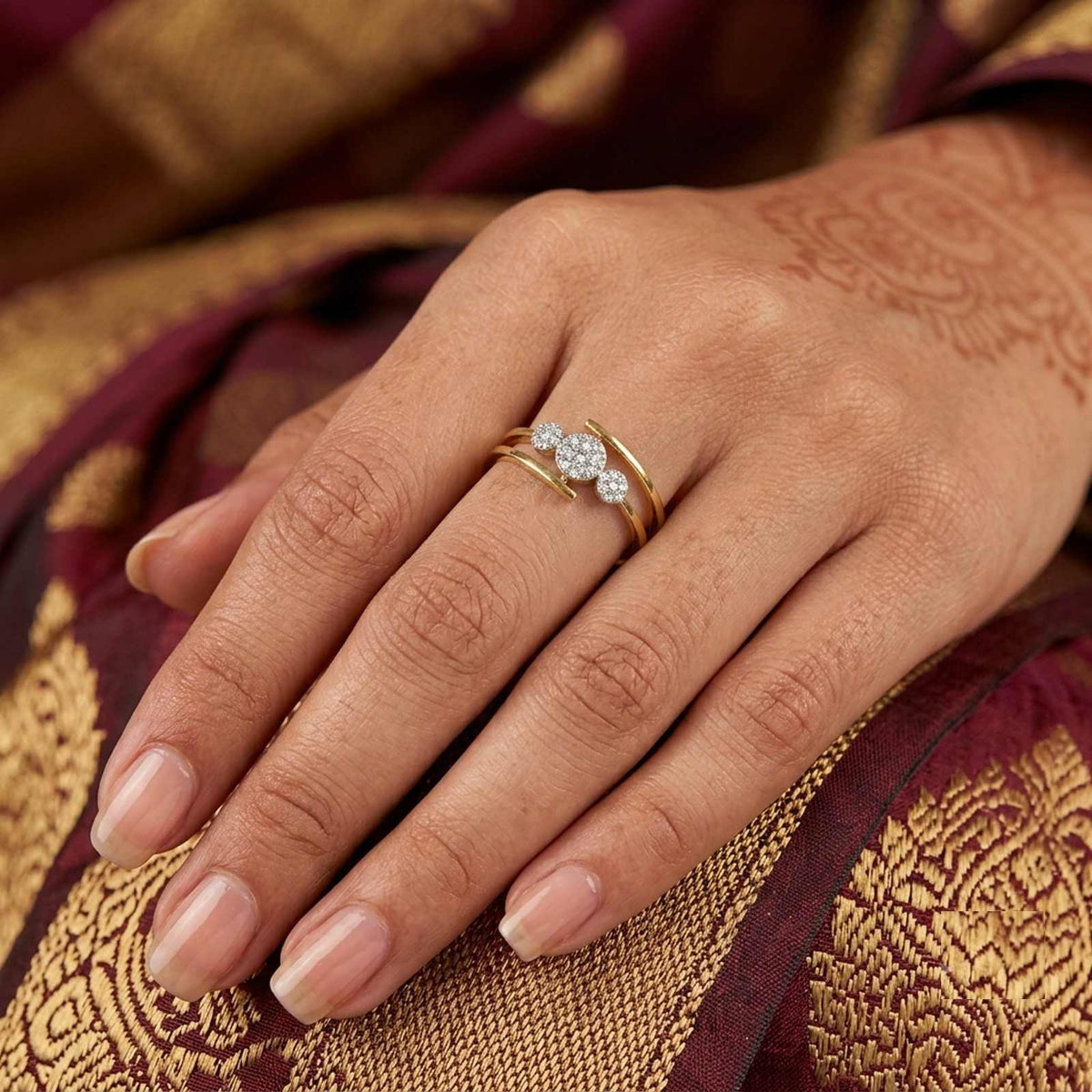 Close-up shot of a gold ring with three diamond-like stones on a background.