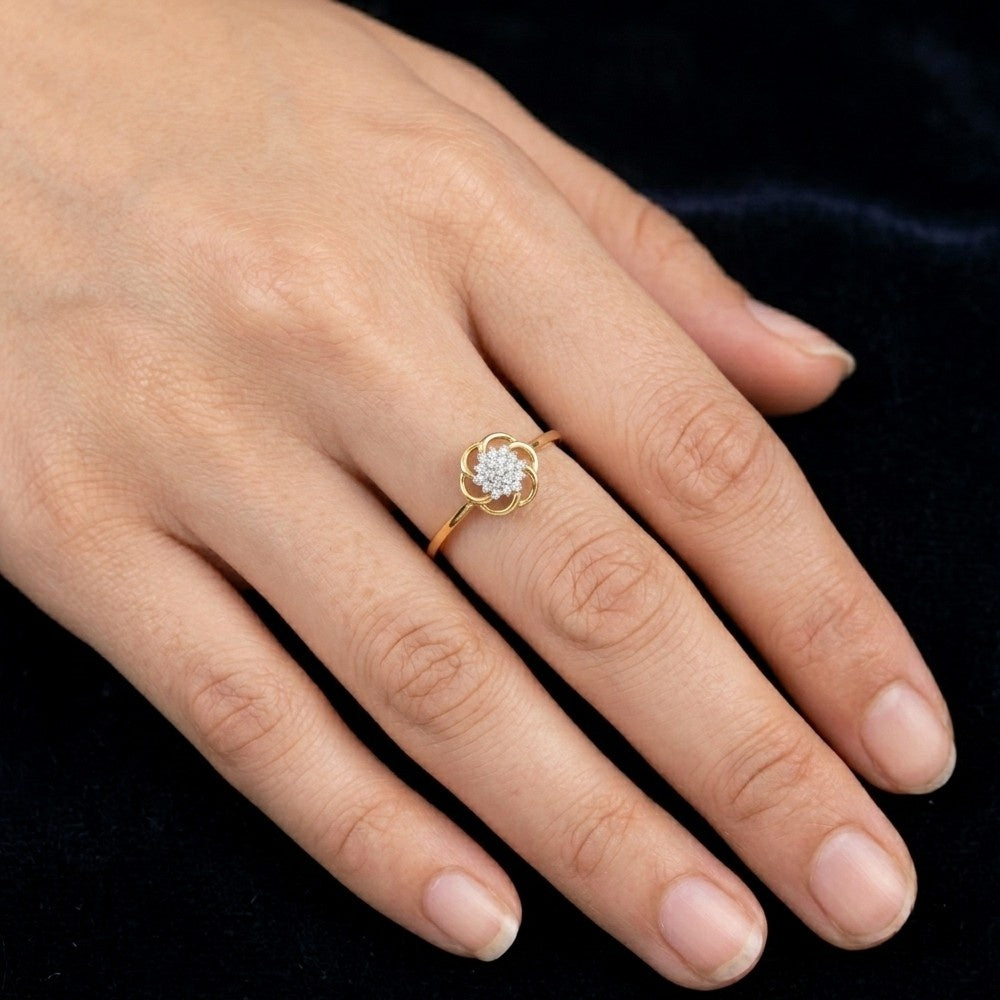 A close-up view of a person's hand wearing a delicate yellow gold ring with a diamond-studded flower motif