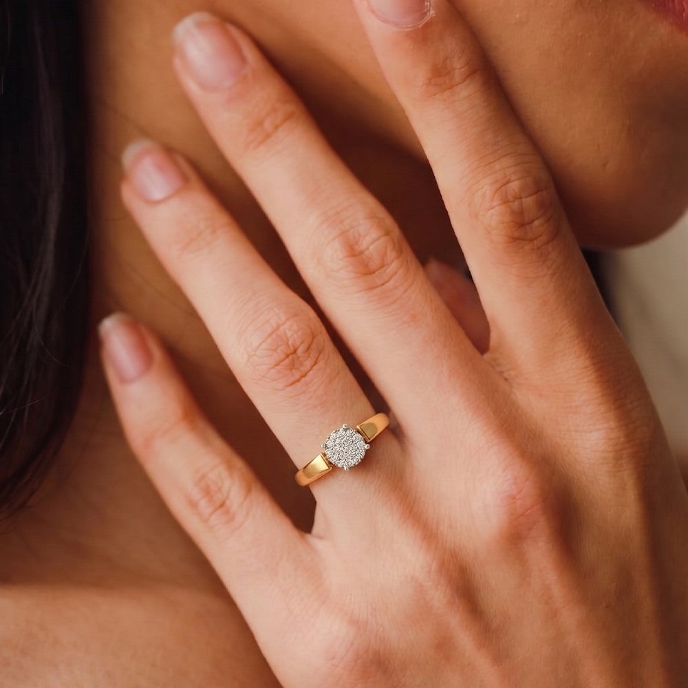 Close-up of a hand wearing a gold and diamond ring with soft focus background