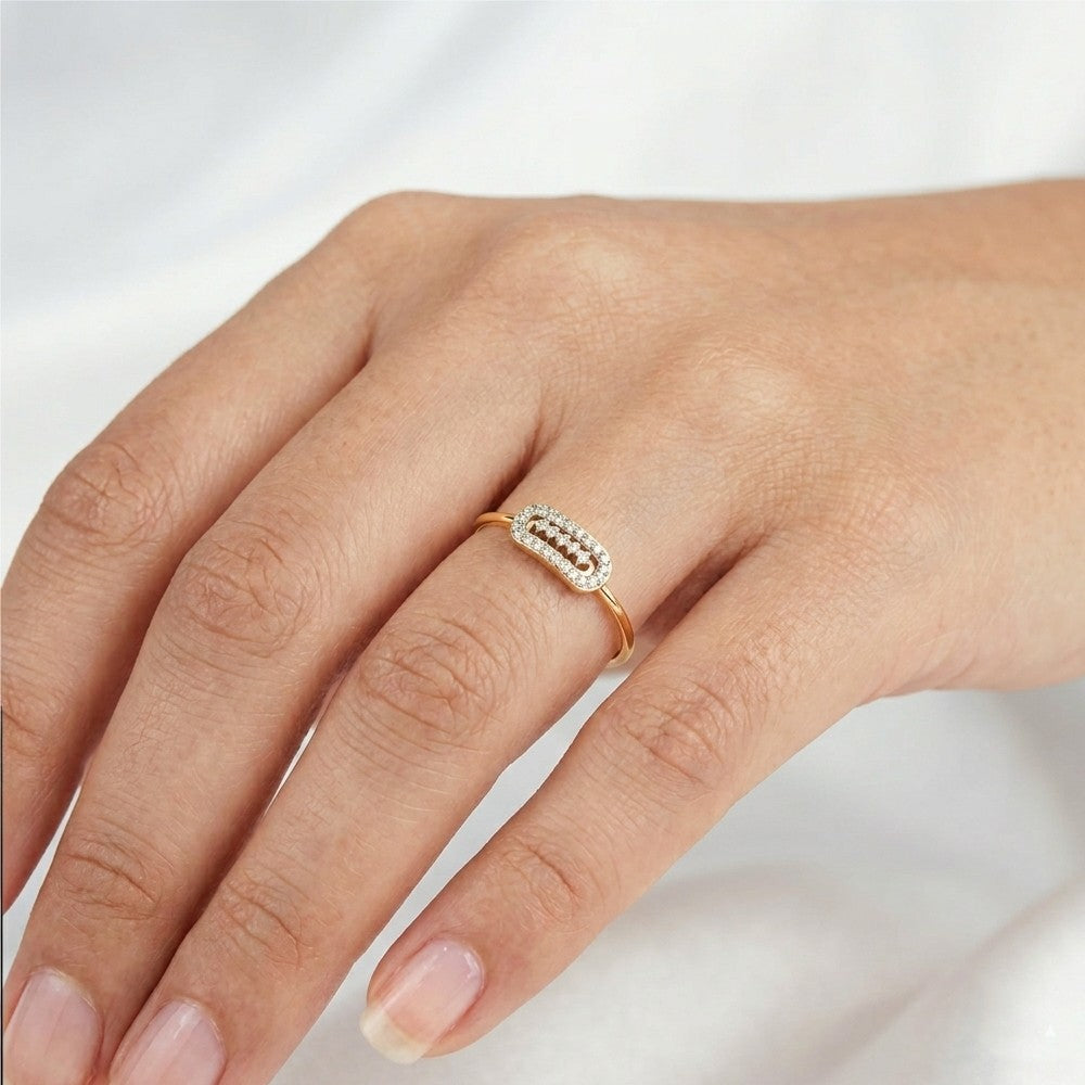 A close-up of a hand wearing a delicate gold ring, set against a soft white fabric background.