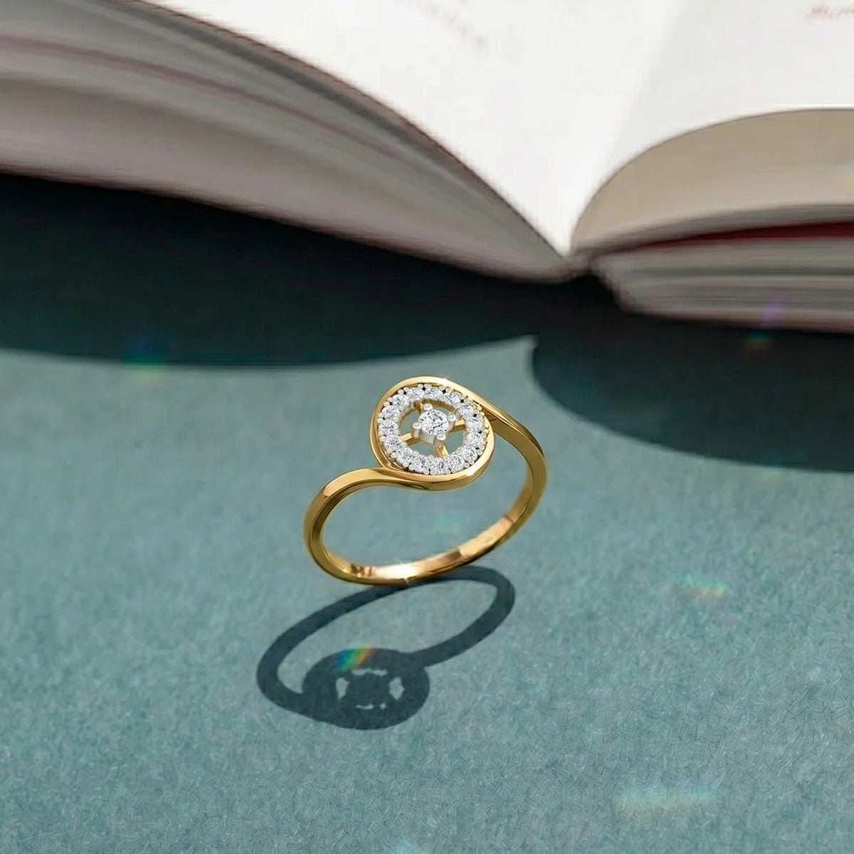 Gold and diamond ring with halo setting on a blue surface. 