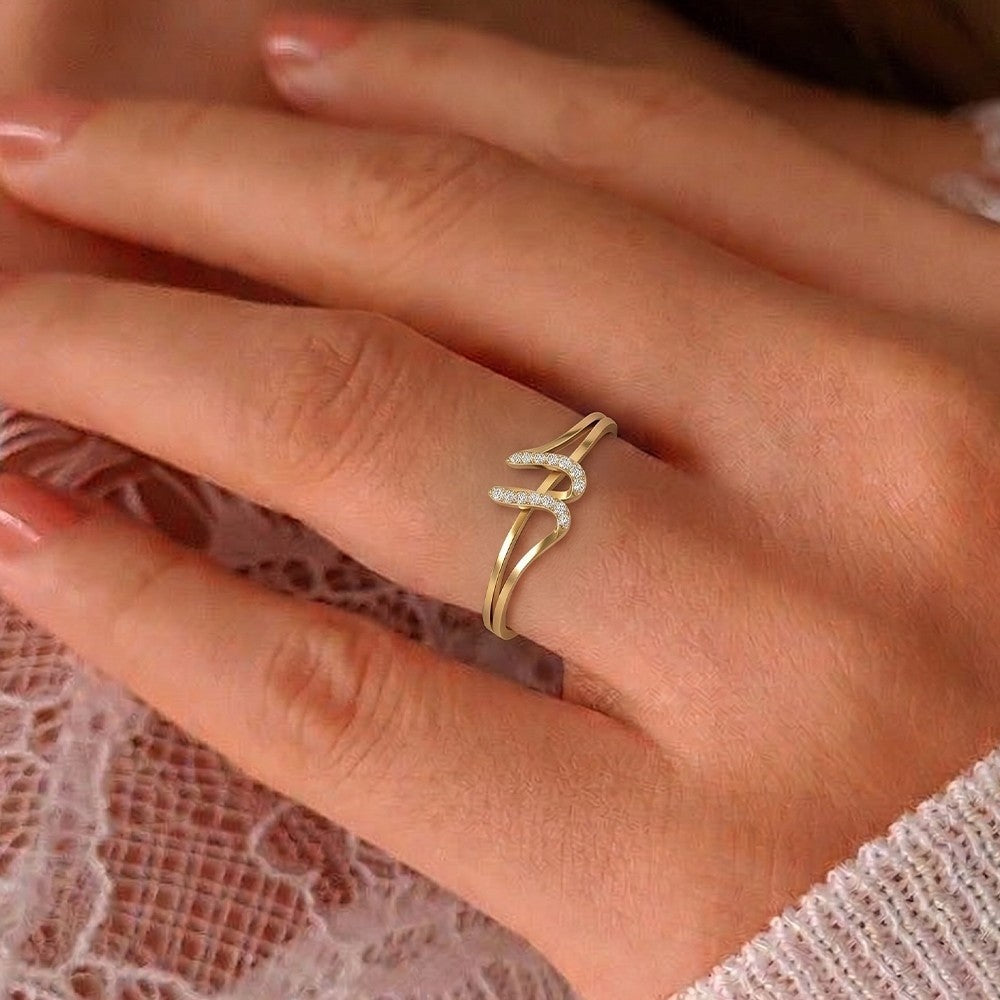 Gold ring with small diamonds on a person's finger against a soft background