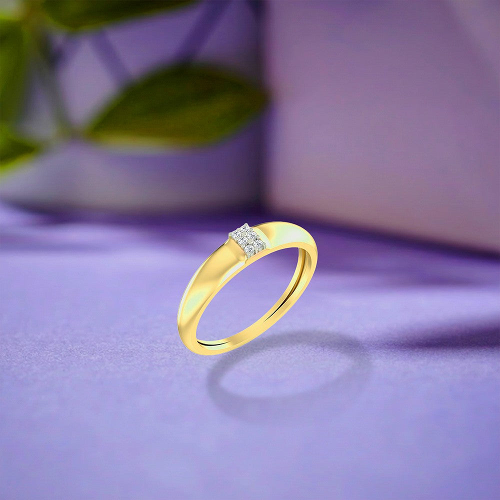 Gold ring with a small diamond cluster on a purple surface.