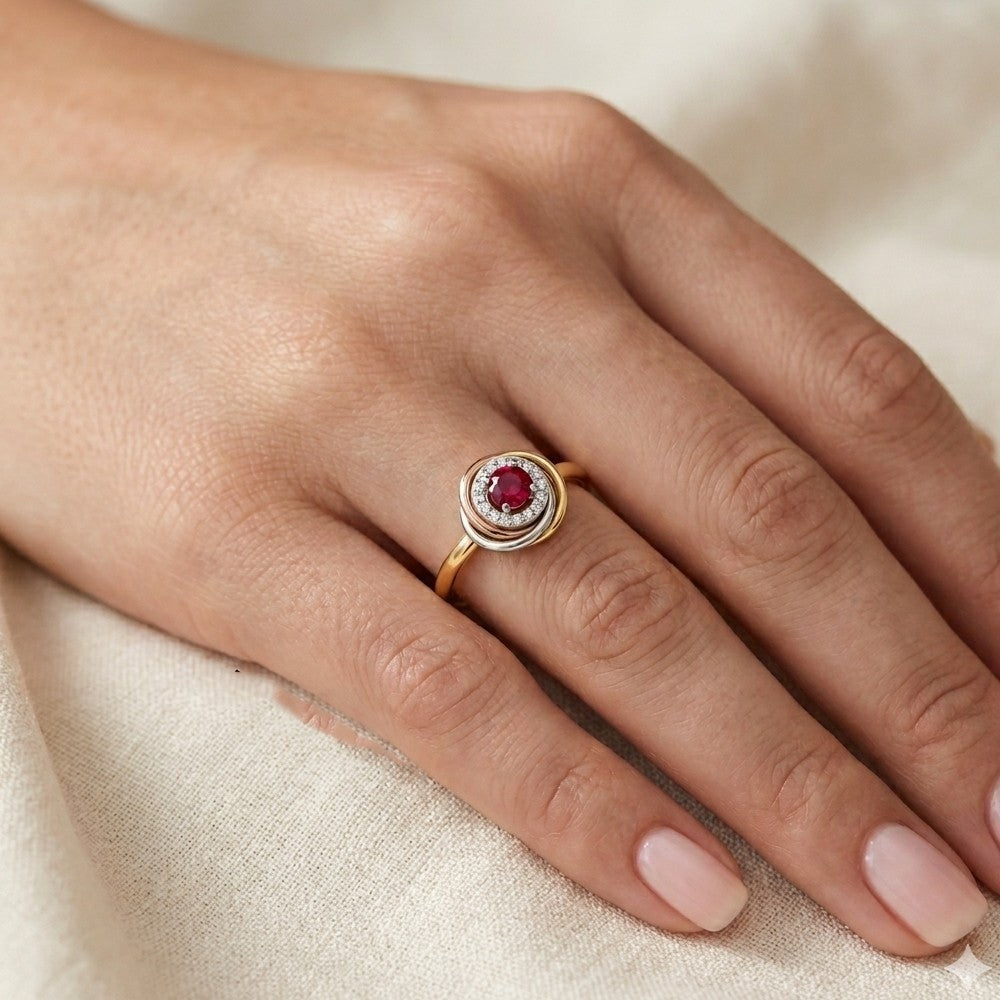 Hand wearing a gold and diamond with ruby gemstone ring.