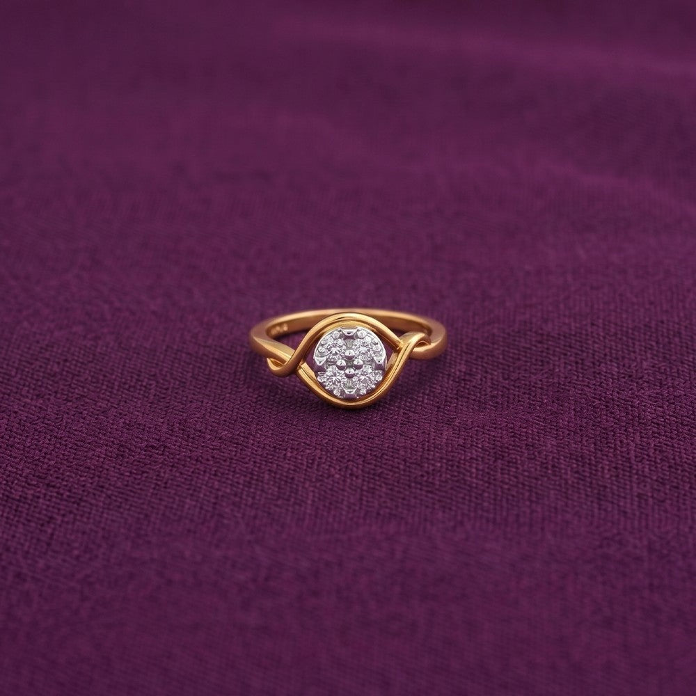 A gold and diamond ring with a round cluster, set against a textured deep purple fabric background.