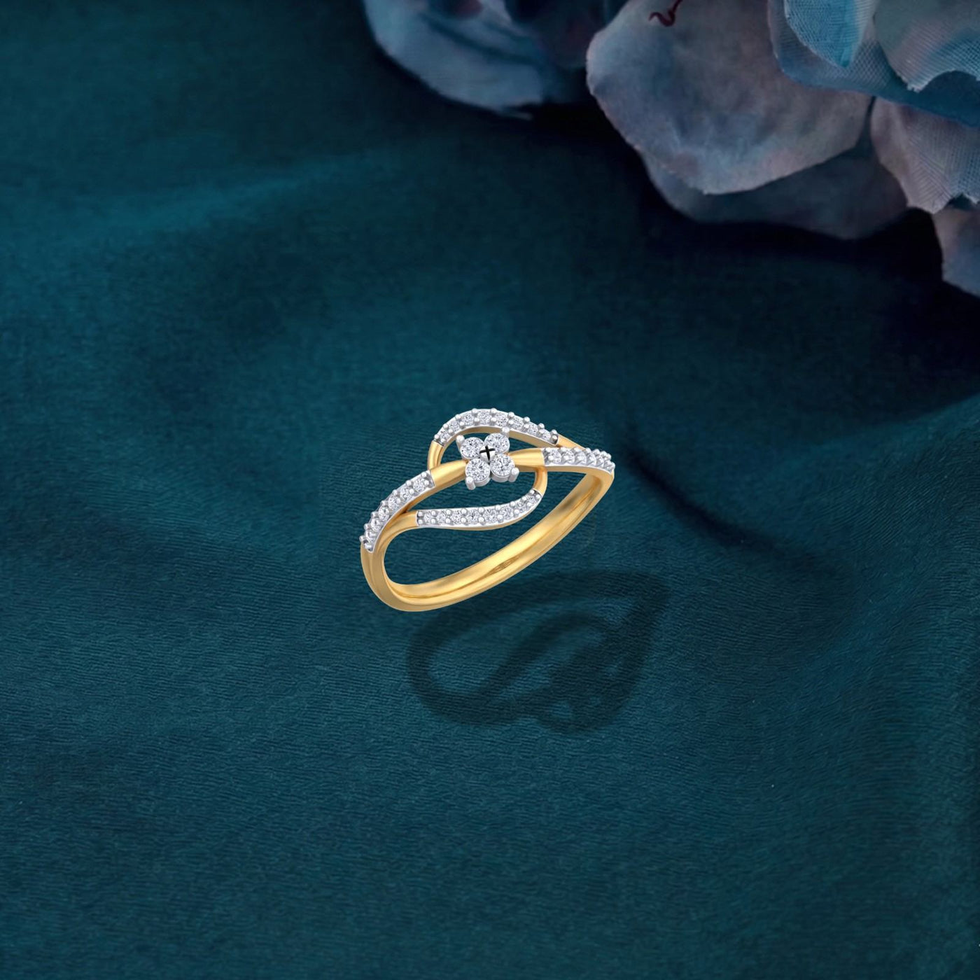 A gold and diamond ring, displayed on a dark teal fabric surface with blurred blue flowers in the background.