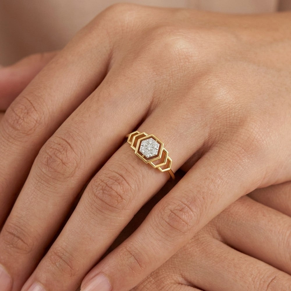 Gold ring with a diamond on a person's finger against a neutral background