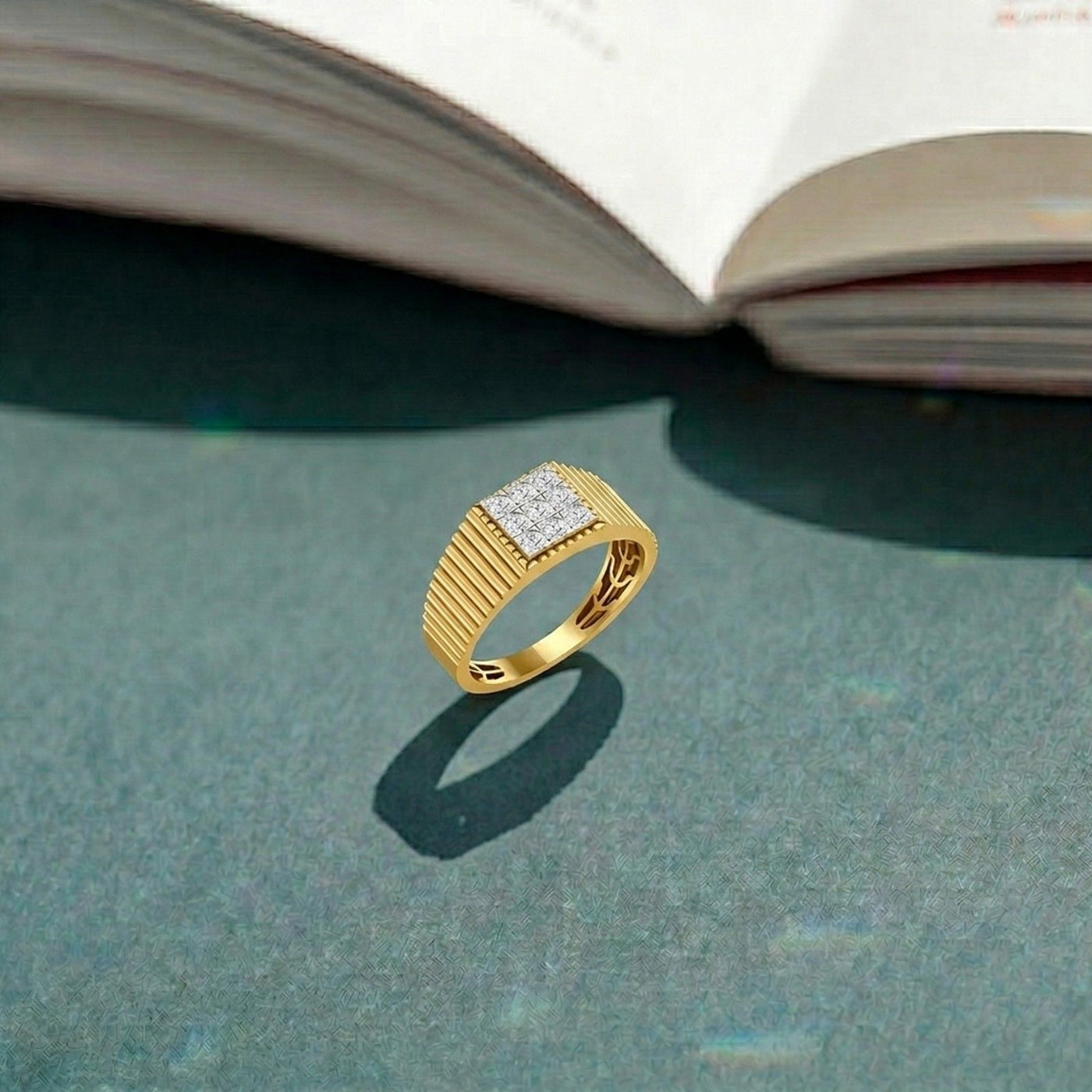 Gold ring with diamond accents on a textured surface with an open book in the background