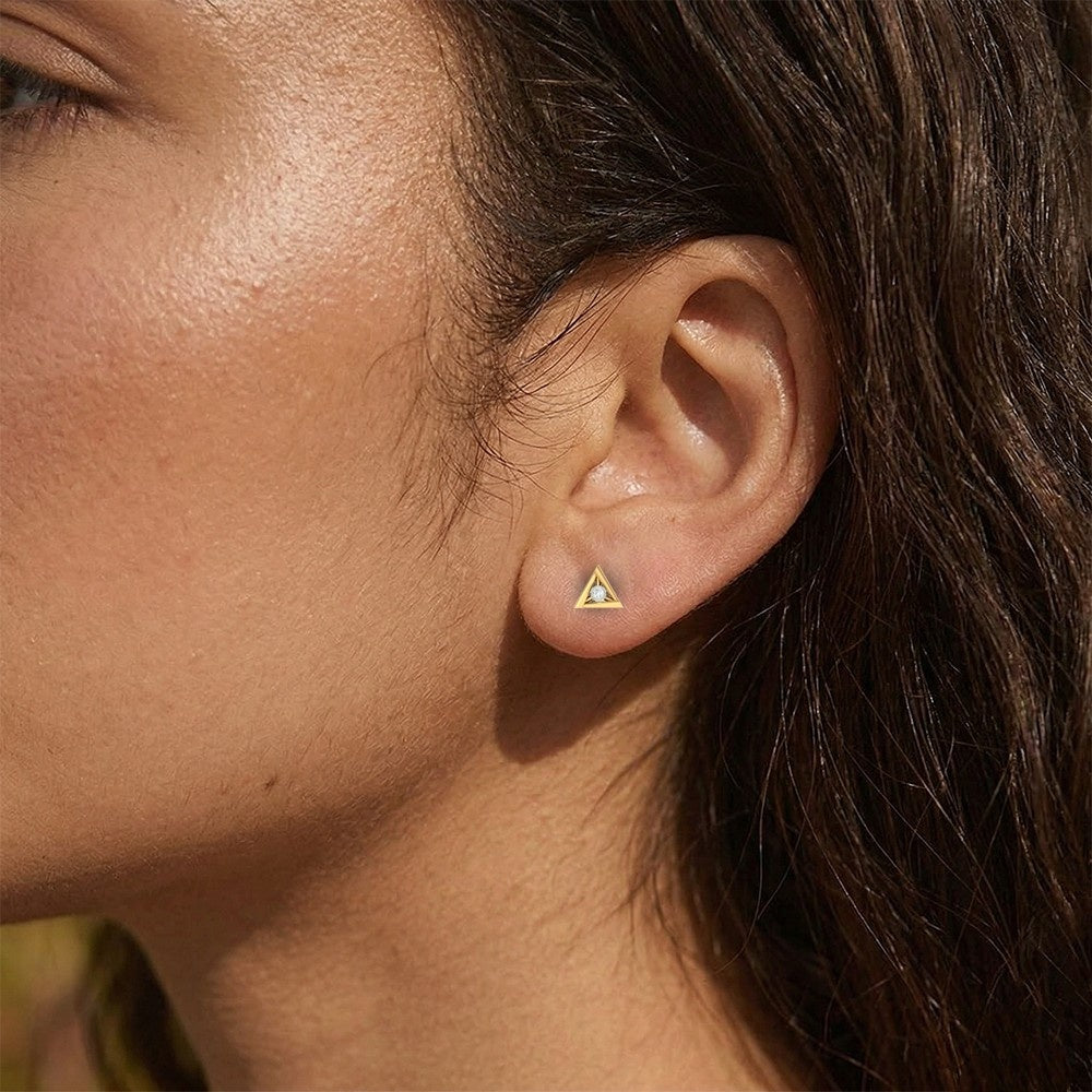 Close-up shot of a gold and diamond triangle-shaped stud earrings.