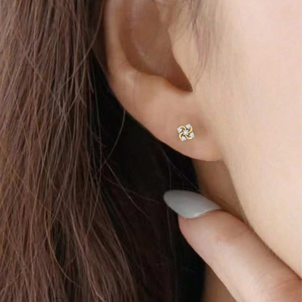 A close-up of a person's ear wearing a gold stud earring with four curved, flower-like gold segments earring.