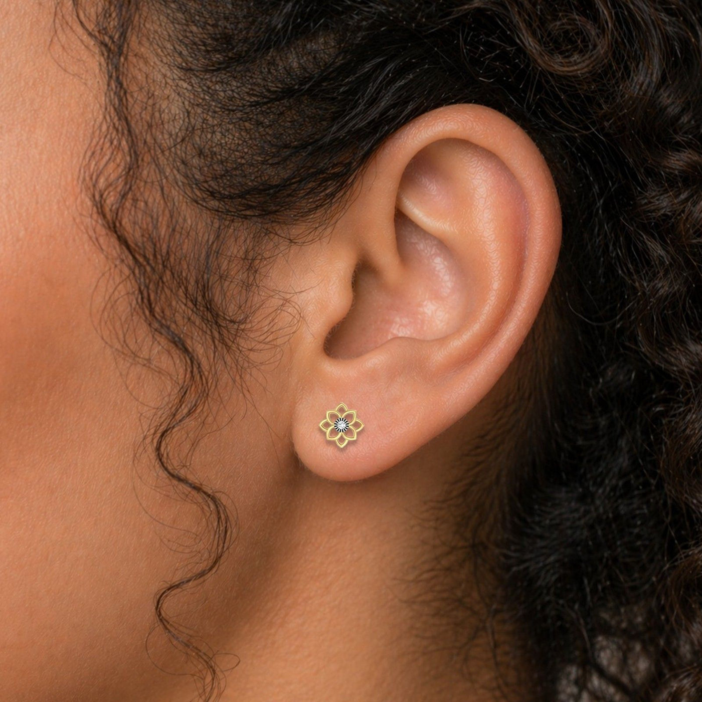 Close-up of an ear wearing a gold spiral earring with dark hair.