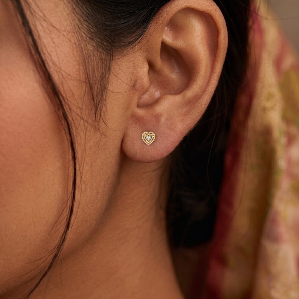 Close-up shot of a gold and diamond heart-shaped stud earrings.