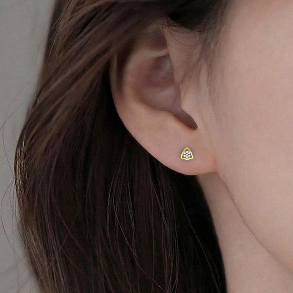 A close-up of a person's ear wearing a gold and diamond earrings.