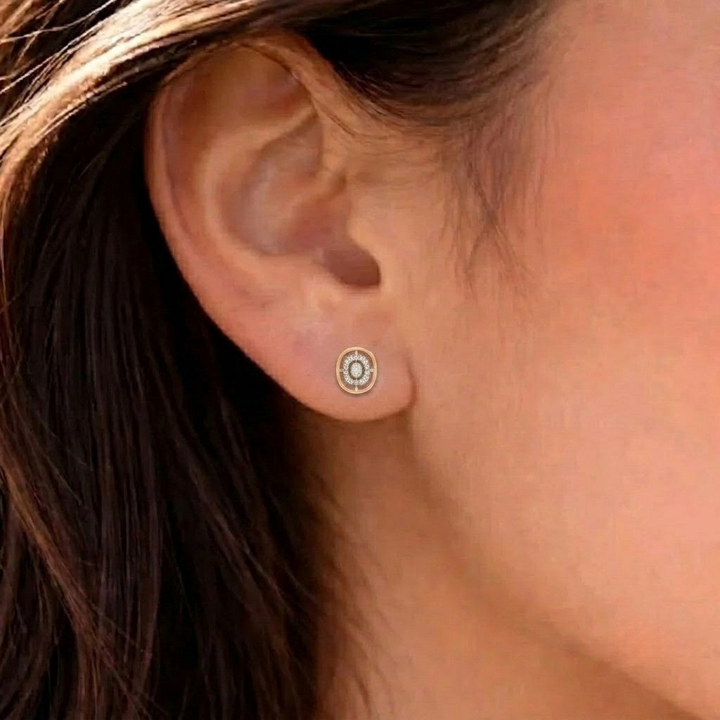 Close-up shot of a gold and diamond oval stud earrings.