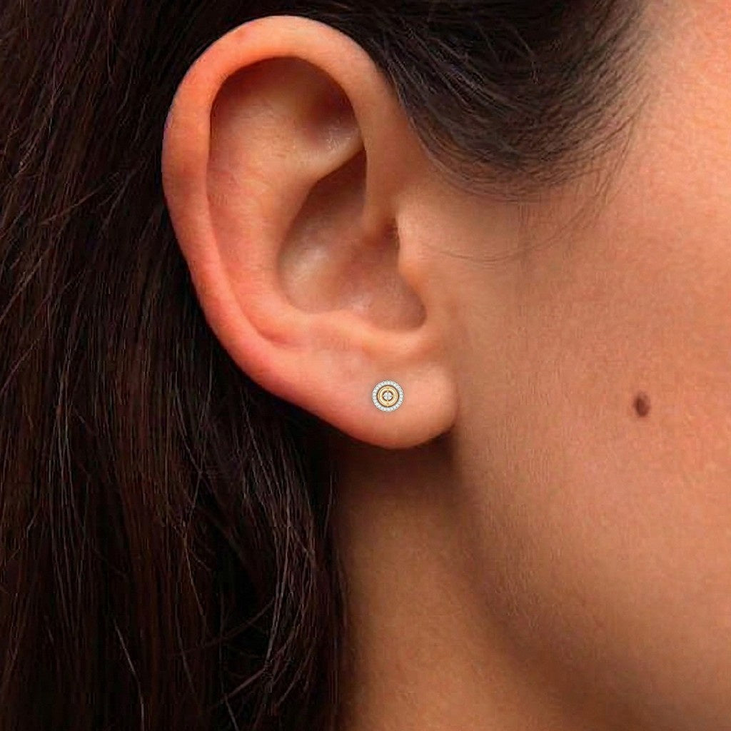 A close-up of a person's ear wearing a circular stud earring.