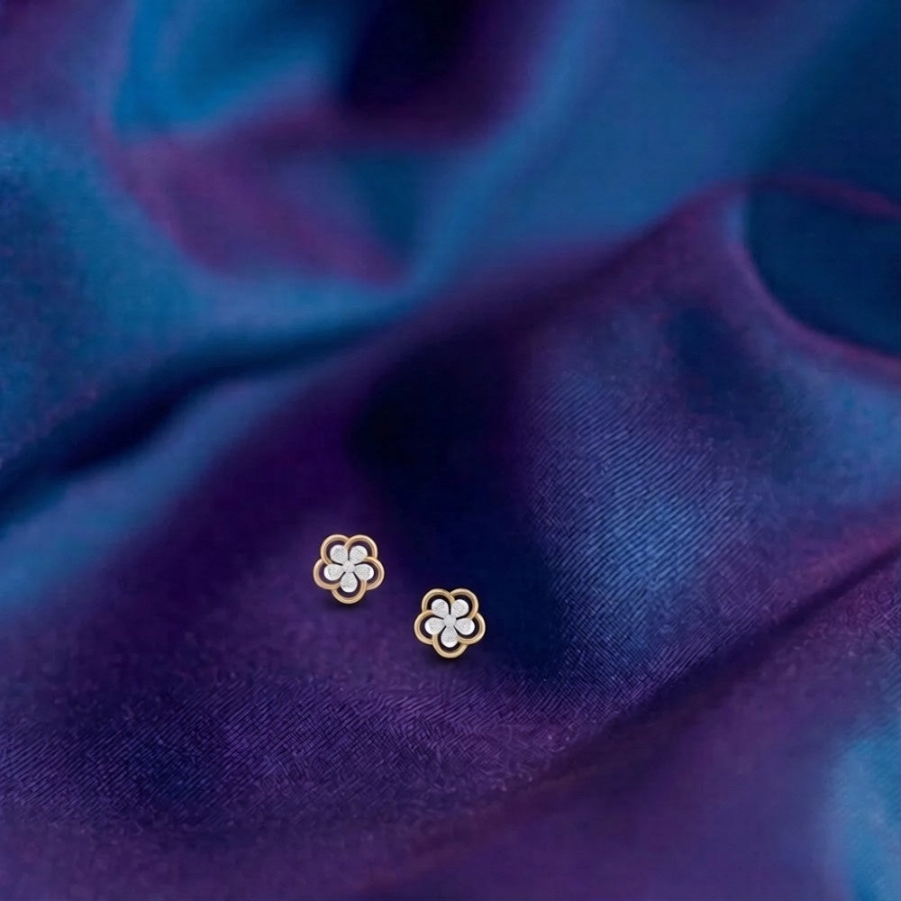 Gold and diamond floral earrings on a blue fabric background