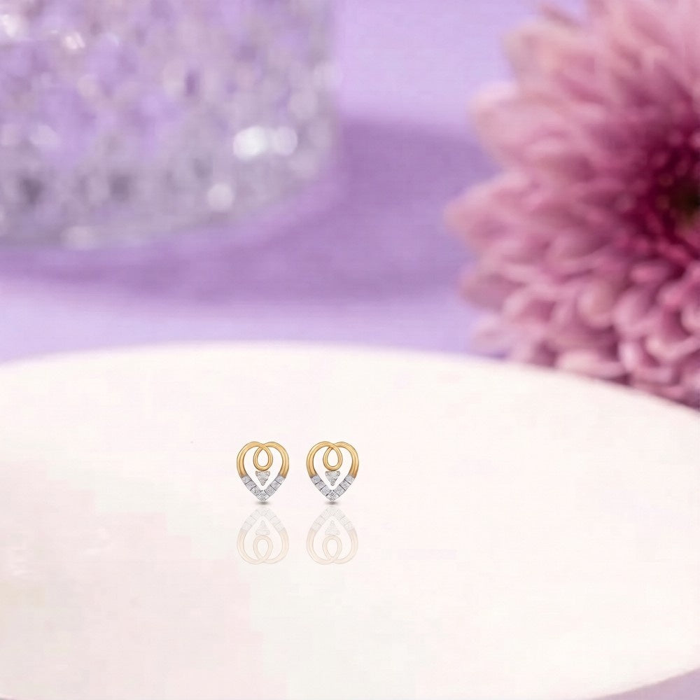 Heart-shaped stud earrings on a white surface with a pink flower background