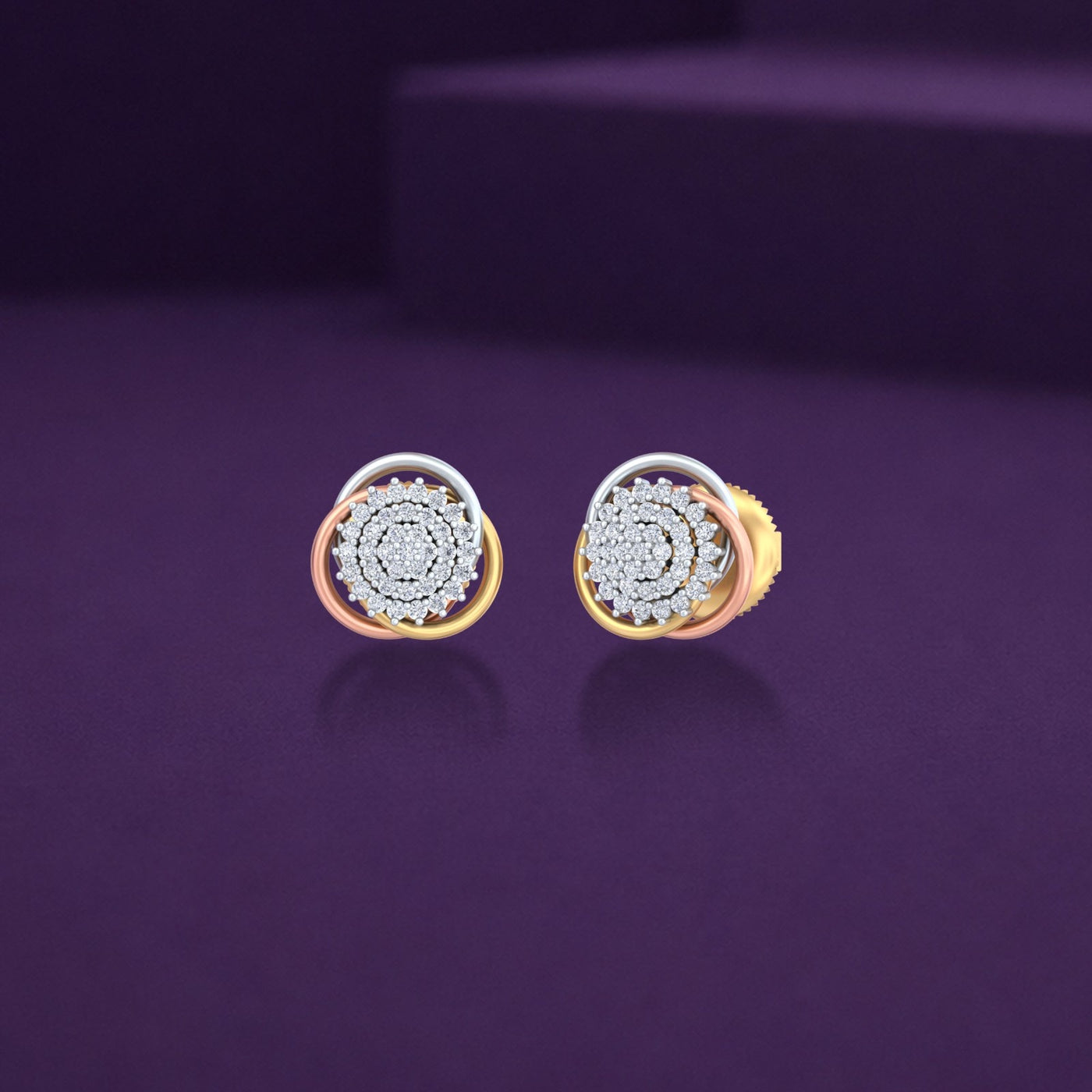A pair of tri-color gold stud earrings with a central diamond cluster against a dark purple background