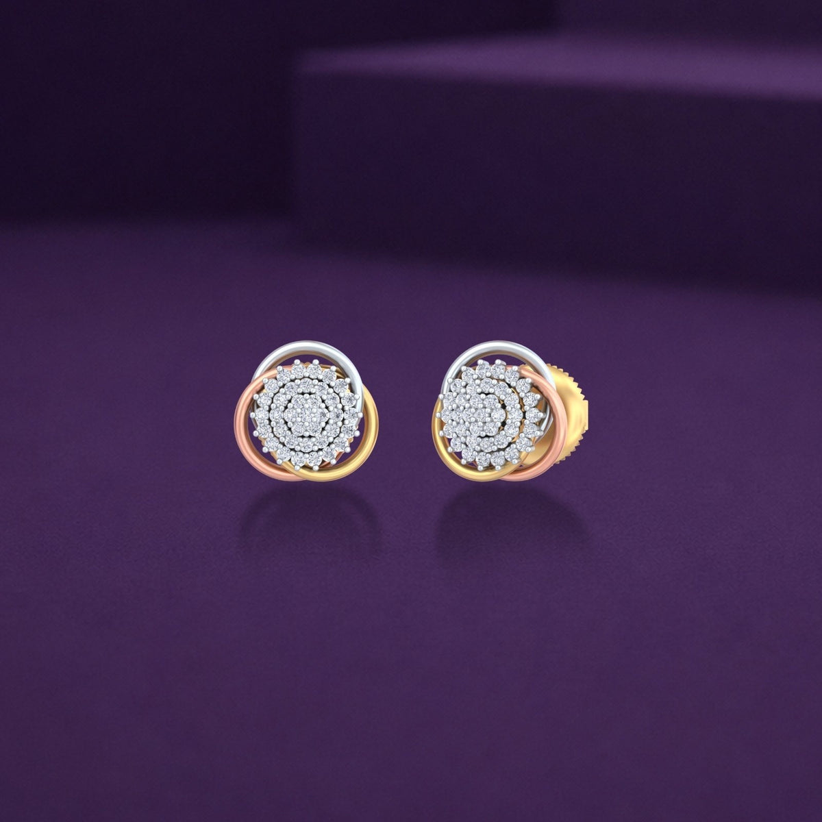 A pair of gold and diamond circular stud earrings with a central cluster, displayed on a dark purple reflective surface.