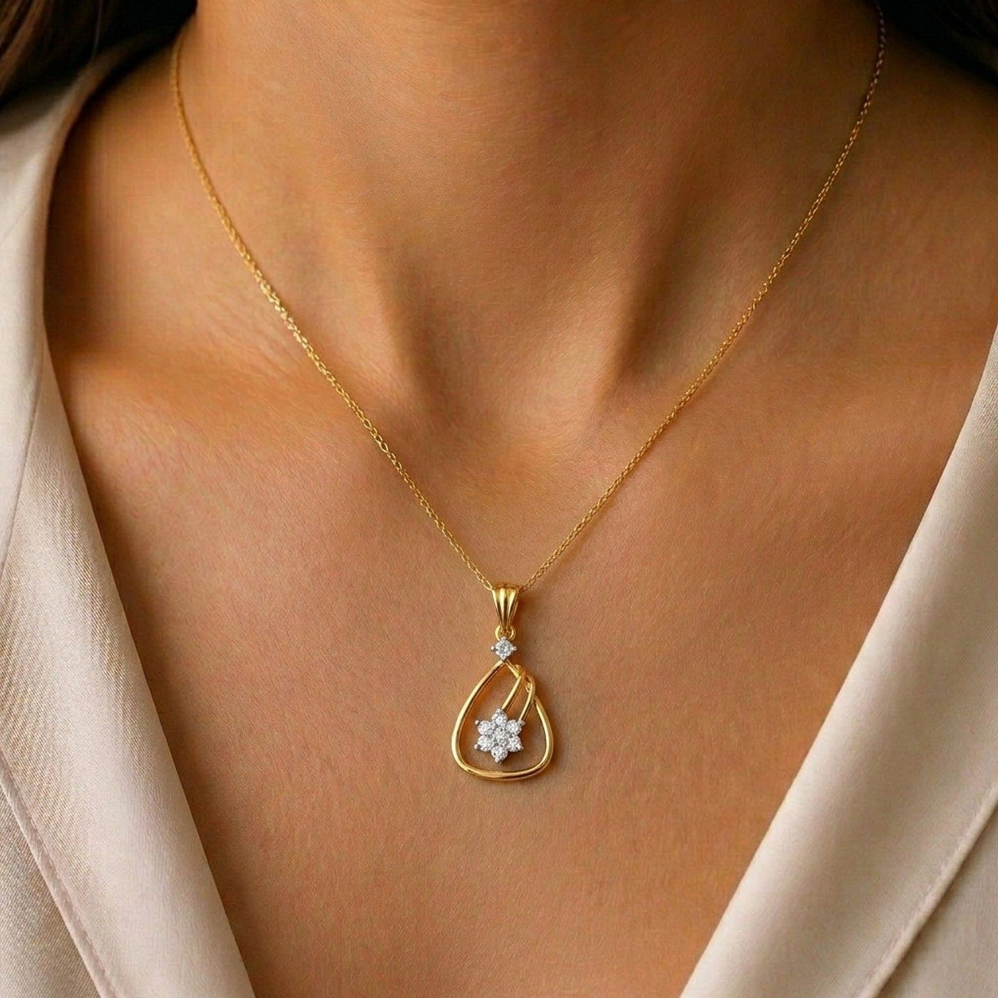 Gold with a diamond pendant on a person wearing a beige top.