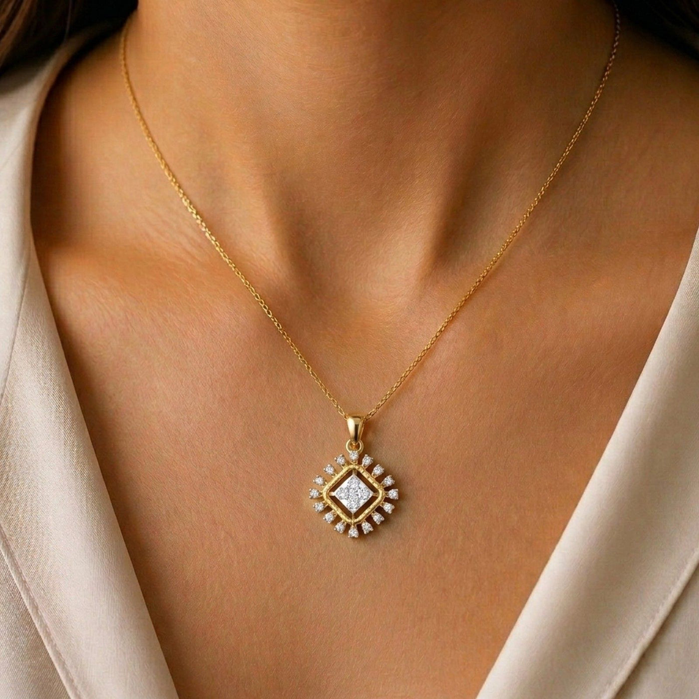 Gold and diamond pendant on a person wearing a beige outfit.