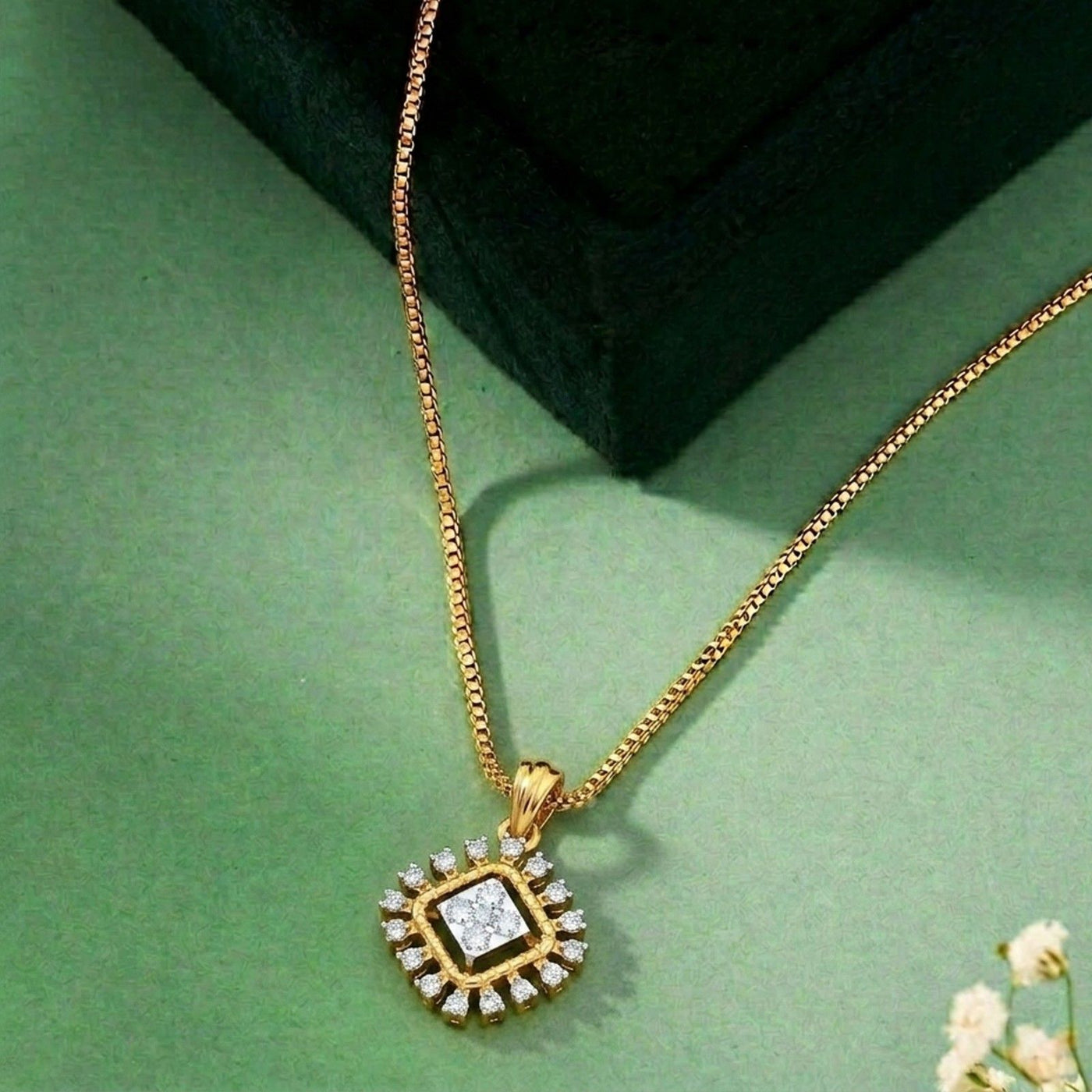 Gold and diamond with a square pendant on a green surface