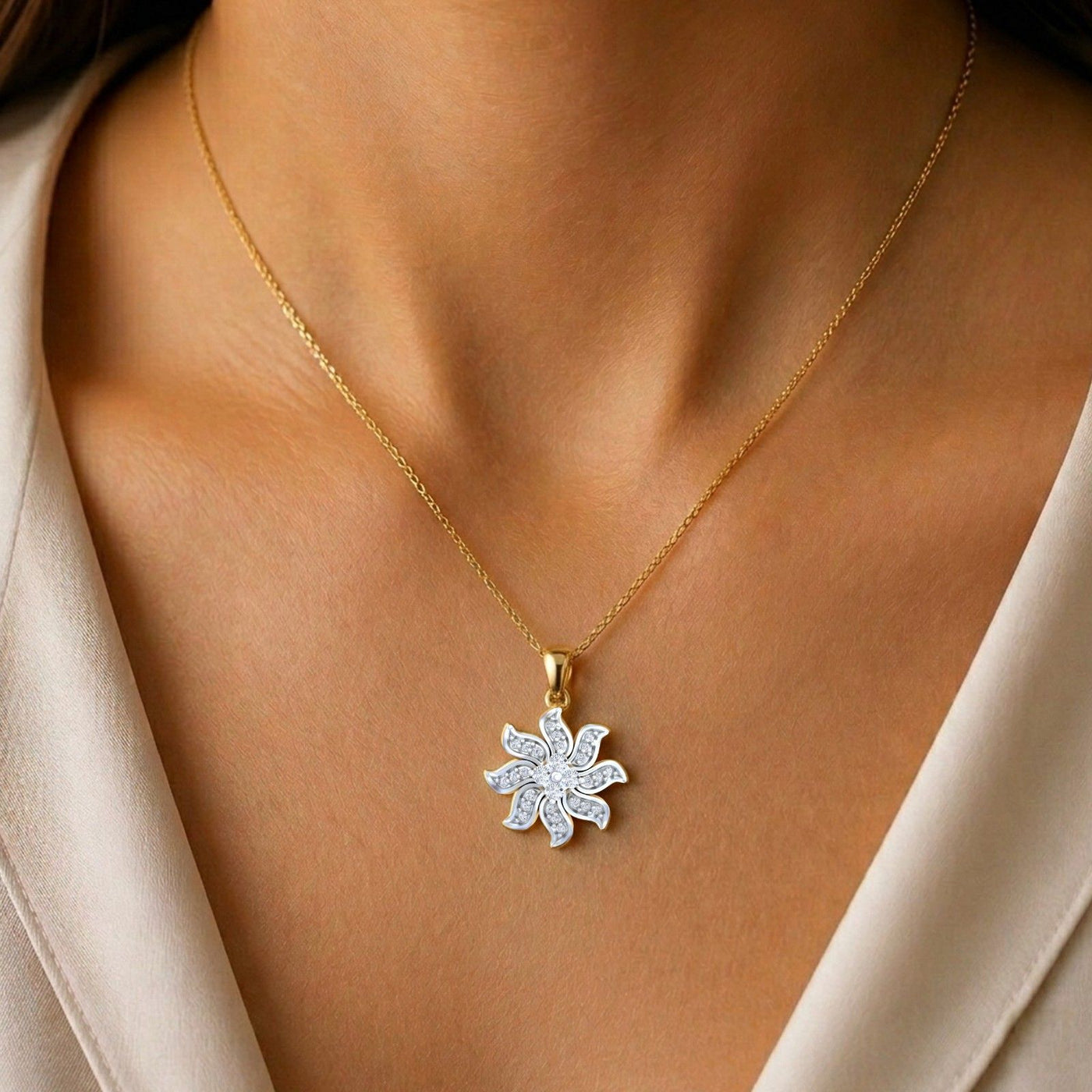 Gold pendant with a diamond flower shape on a person wearing a beige top.