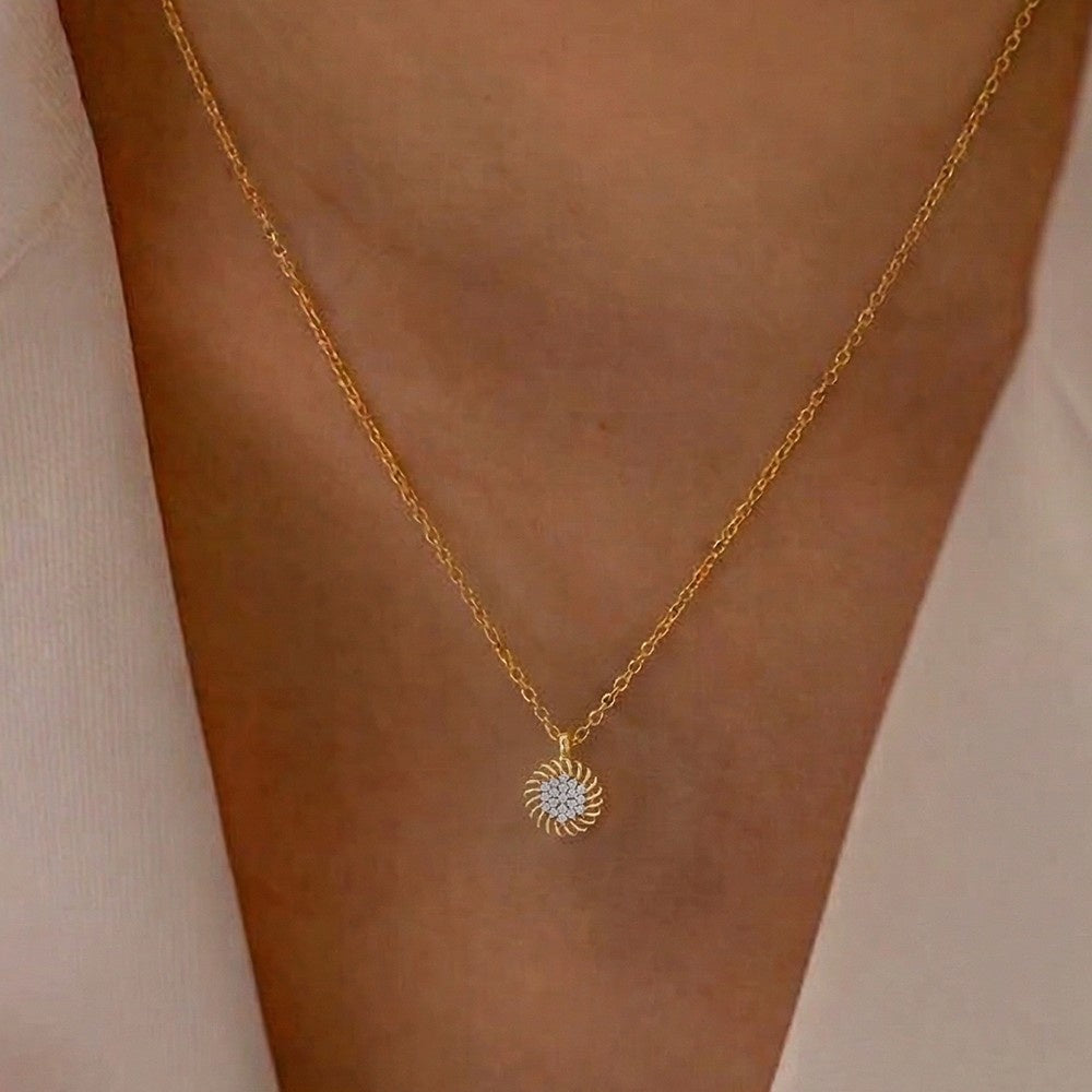 Gold and diamond sun-shaped pendant on a person's neck