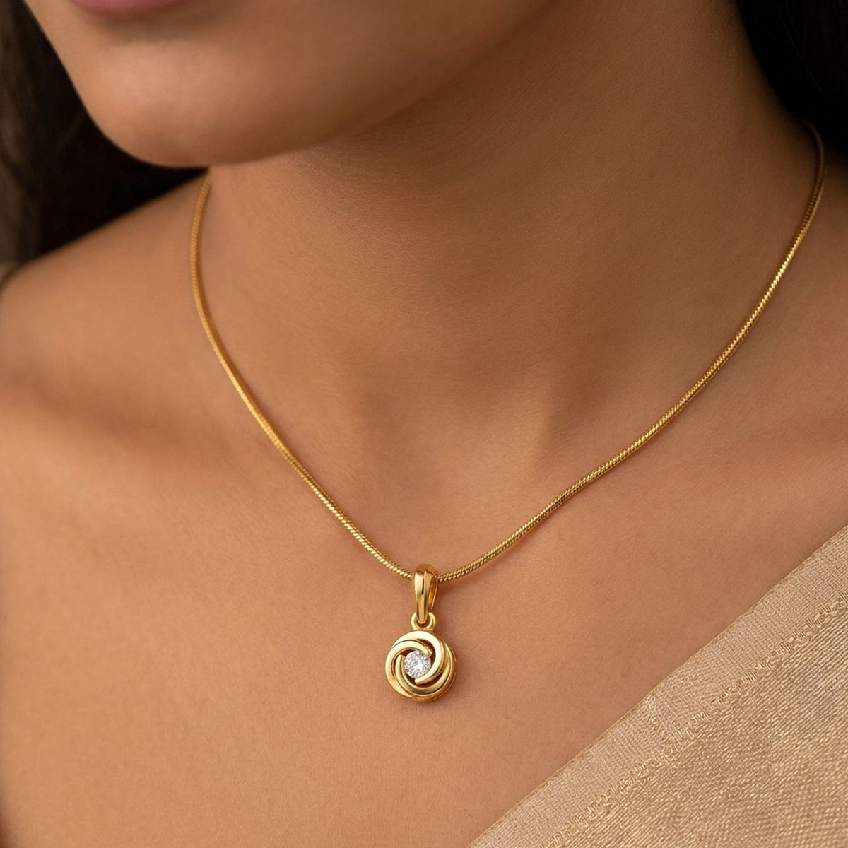 A gold pendant with a circular swirl  featuring a clear central diamond, displayed against a person neck.