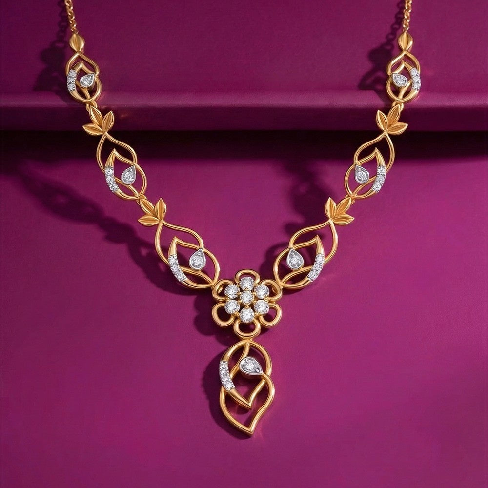 Gold necklace featuring leaf-shaped links studded with small diamonds, a central floral cluster pendant, and a dangling leaf-shaped drop, displayed on a magenta background.